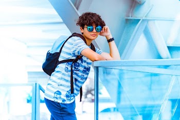 Man Wearing Blue and White Stripe Shirt Leaning on Stainless Steel Handrail