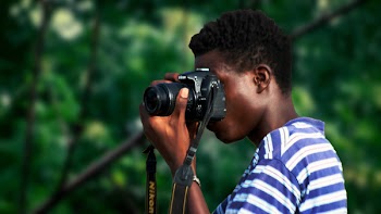 Man Wearing Blue And White Striped Shirt Using Nikon Camera