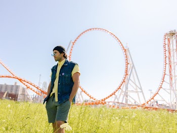 Man Wearing Blue Button-up Sleeveless Vest and Yellow Shirt Standing Near Roller Coaster