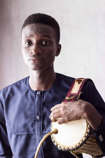 Man Wearing Blue Crew-neck Long-sleeved Shirt Standing While Holding Brown Musical Drum