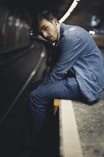 Man Wearing Blue Denim Jacket and Blue Denim Jeans Sitting on Gray Surface