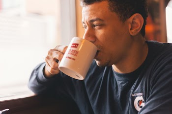 Man Wearing Blue Gatorade Sweater Sipping on Cup