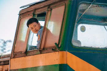 Man Wearing Blue Shirt Driving Green and Yellow Vehicle