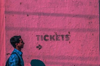 Man Wearing Blue Sports Shirt and Backpack Passing Through Pink Wall