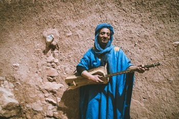 Man Wearing Blue Top Holding Brown String Instrument