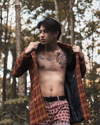Man Wearing Brown and Yellow Plaid Coat Across Green Trees