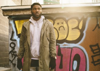 Man Wearing Brown Jacket standing against colorful graffiti wall