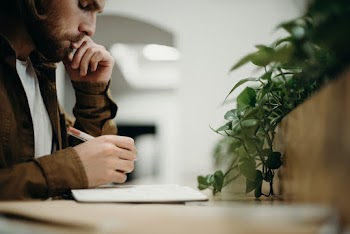 Man Wearing Brown Jacket Using Pen
