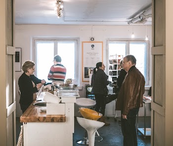 Man Wearing Brown Leather Jacket Standing in Front of Desk With Woman Wearing Black Cardigan
