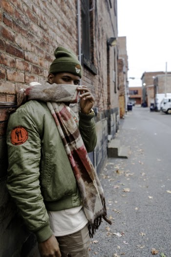 Man Wearing Bubble Jacket With Scarf Leaning on Wall