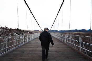 Man Wearing Cap Walking Along Bridge