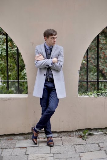 Man Wearing Coat Crossing Legs While Leaning On Wall