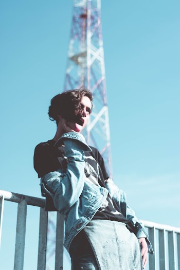 Man Wearing Denim Jacket Leaning on Railing