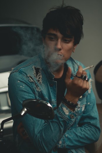 Man Wearing Distressed Denim Jacket Blowing Smoke of Cigarette