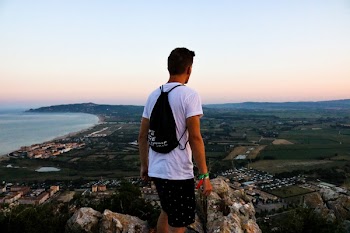 Man Wearing Drawstring Bag Standing On Top Of Mountain