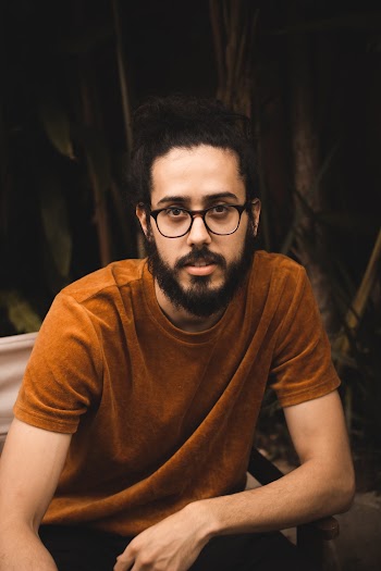Man Wearing Eyeglasses and Brown Shirt Sitting on Chair