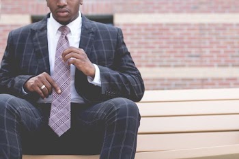 man wearing formal coat sitting on beige wooden bench