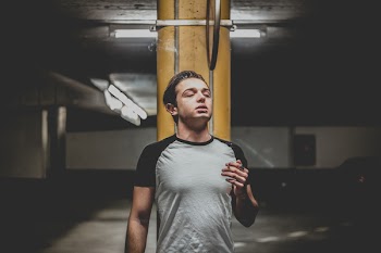 Man Wearing Gray and Black Raglan T-shirt Standing Near Orange Post