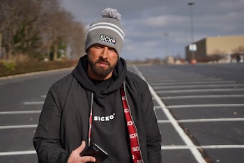 Man Wearing Gray and White Bobblehat Standing in Road