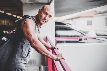 Man Wearing Gray Apron Placing His Hands on Red Metal Handrail