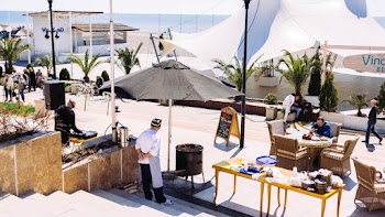 Man Wearing Gray Apron Standing Under Gray Parasol