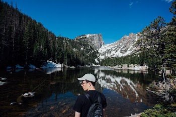 man wearing gray cap standing infront of body of water