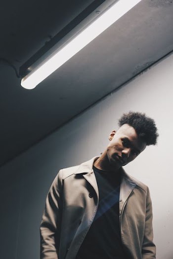 man wearing gray coat near white wall