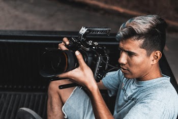 Man Wearing Gray Crew-neck Shirt and Gray Cargo Short Using Black Camera