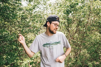 Man Wearing Gray Crew-neck T-shirt Standing Behind Bush