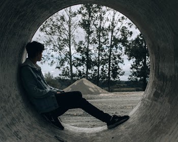 Man Wearing Gray Jacket Leaning on Gray Metal Hole Viewing Trees and Mountain