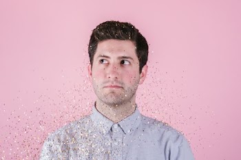 man wearing gray polo shirt behind pink background close-up photo
