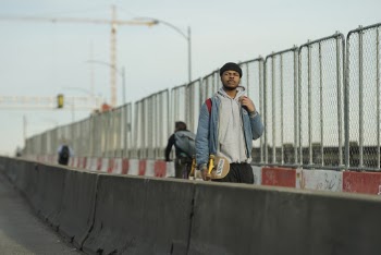 Man Wearing Gray Pullover Hoodie and Blue Zip Bubble Jacket Carrying Skateboard