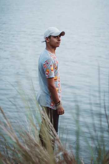 Man Wearing Gray Shirt Standing Beside Body of Water