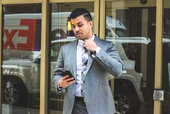 Man Wearing Gray Suit Holding Black Smartphon