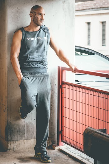 Man Wearing Gray Tank Top and Track Pants Leaning on Wall