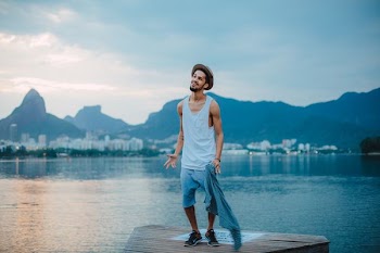 man wearing gray tank top near the body of water