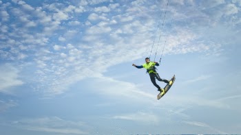 Man Wearing Green and Black Wetsuit Riding Wakeboard