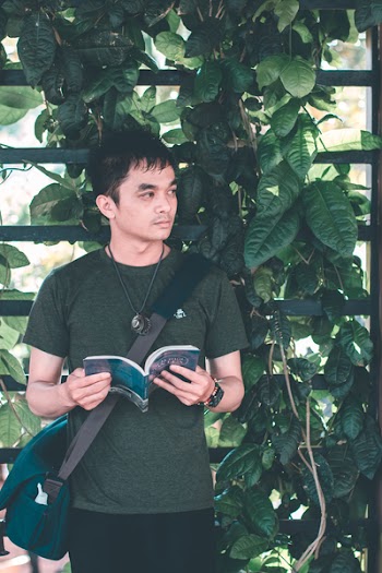 Man Wearing Green Shirt Standing Near Black Wall