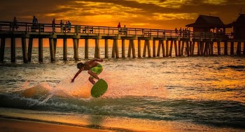 Man Wearing Green Shorts Surfing during Golden Hour