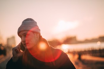 man wearing grey beanie while using telephone