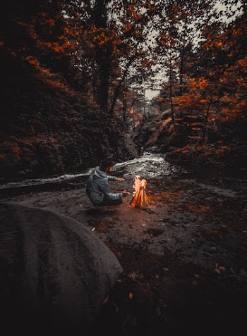 Man Wearing Grey Hoded Jacket Beside Bonfire