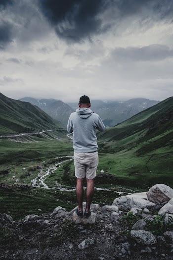 Man Wearing Grey Hooded Jacket Standing on the Cliff