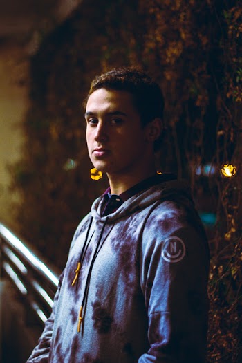 Man Wearing Grey Pullover Hoodie Standing Near Vine Plant With String Lights