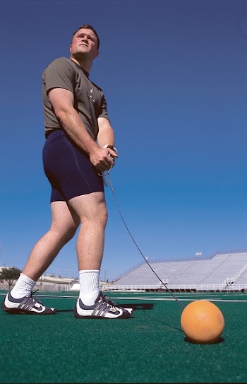 Man Wearing Grey Shirt Swinging Orange Ball