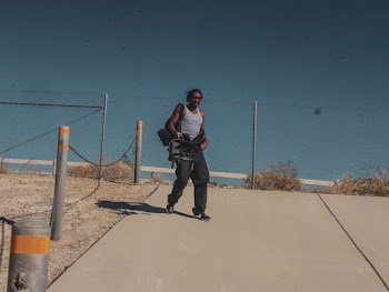 Man Wearing Grey Tank Top And Black Pants Carrying Bag