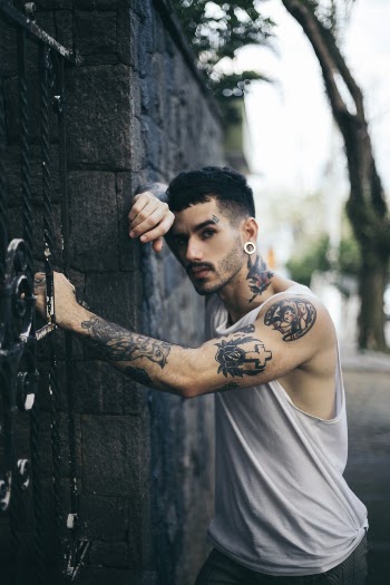 Man Wearing Grey Tank Top Leaning On Gate
