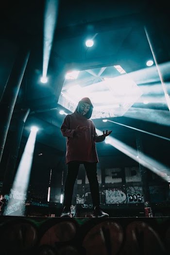 man wearing Guy Fawkes mask standing on stage