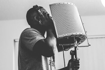 man wearing headphones while singing in front of microphone inside studio