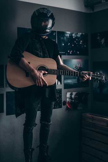 Man Wearing Helmet and Holding Guitar