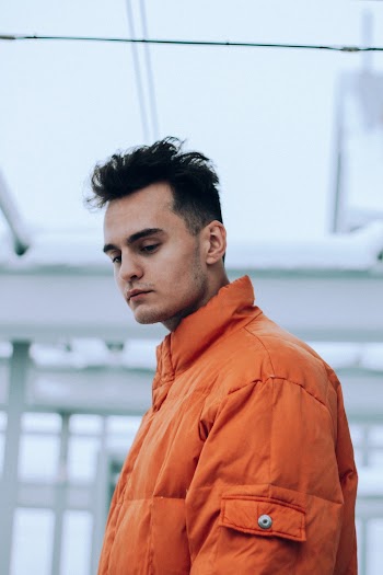 Man Wearing Orange Bubble Jacket Standing While Looking Down
